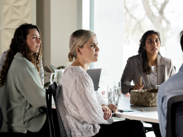 three women sit at a table in a business meeting
