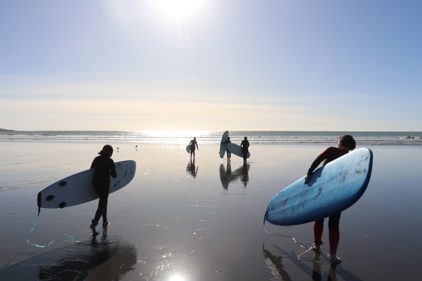 Young women heading out for a surf, supported to participate by the WaterBoy’s surf club programme.