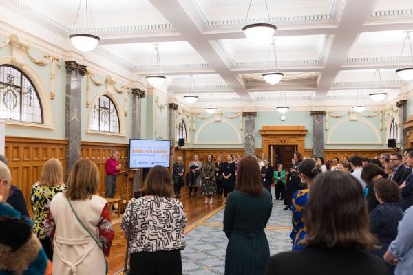 Denise Mackay stands on stage addressing room of 50 people at the dress for success event.