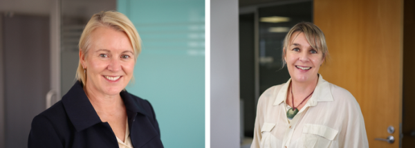 Two blond women look at the camera smiling. They are standing inside in an office setting.