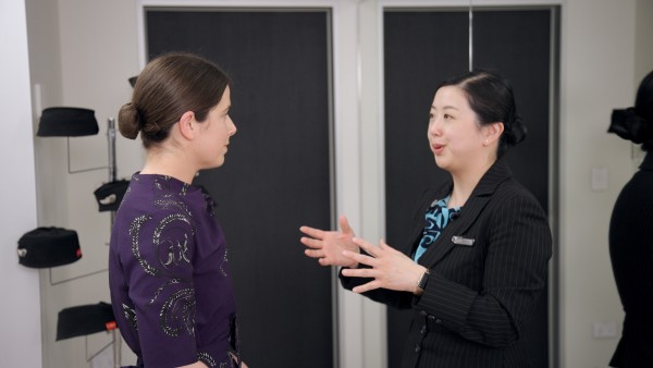 Lucy from Air NZ trying on a new uniform in purple chiffon with grey kowhai patterns. 