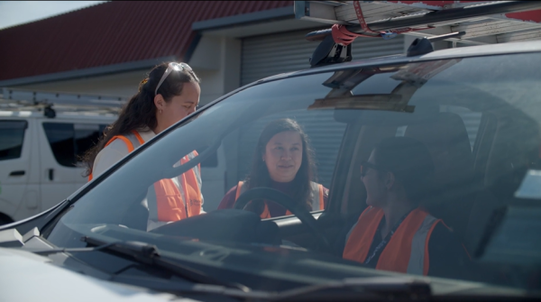 Two women talking to a third women in a ute