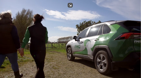 Two women walking towards a grey and green FMG branded SUV
