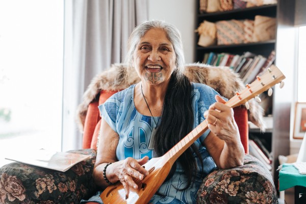 Older women in armchair playing a ukelele