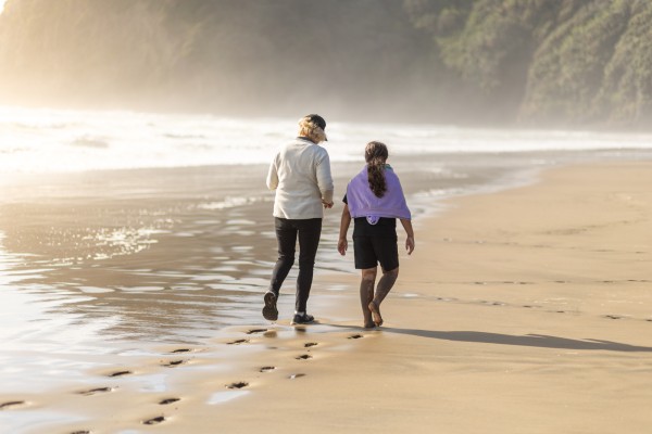 Grandmother and grandchild walking on beach
